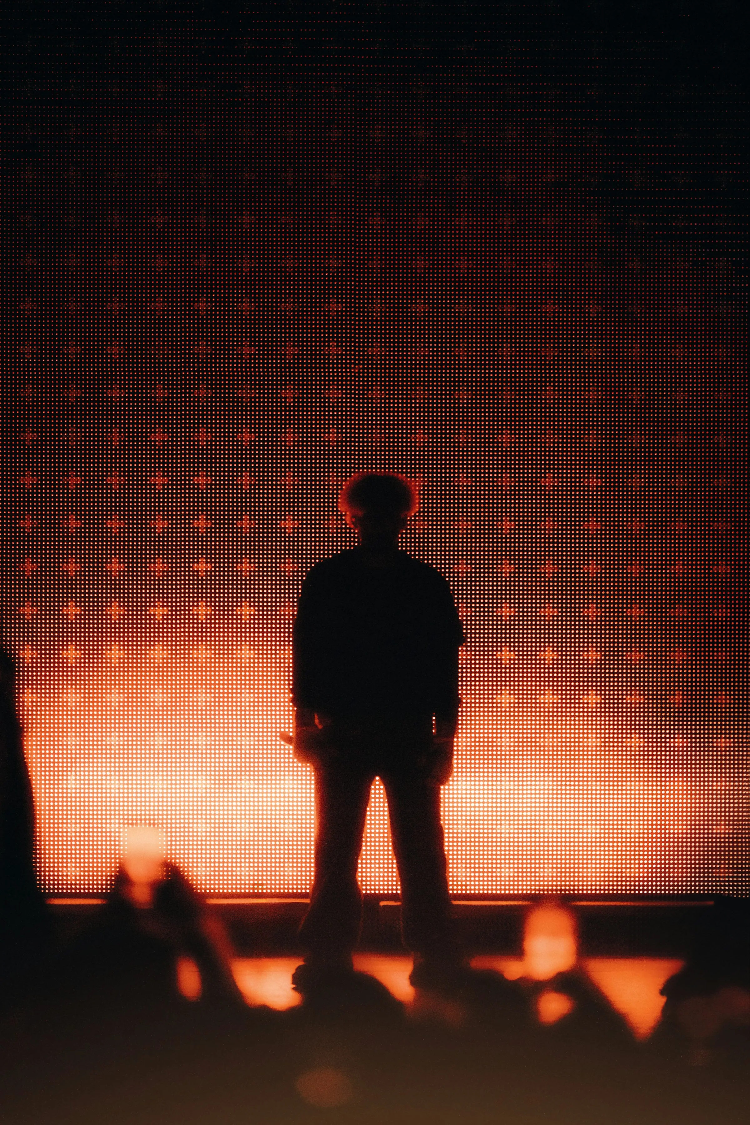 A lone performer silhouetted on stage under deep red light